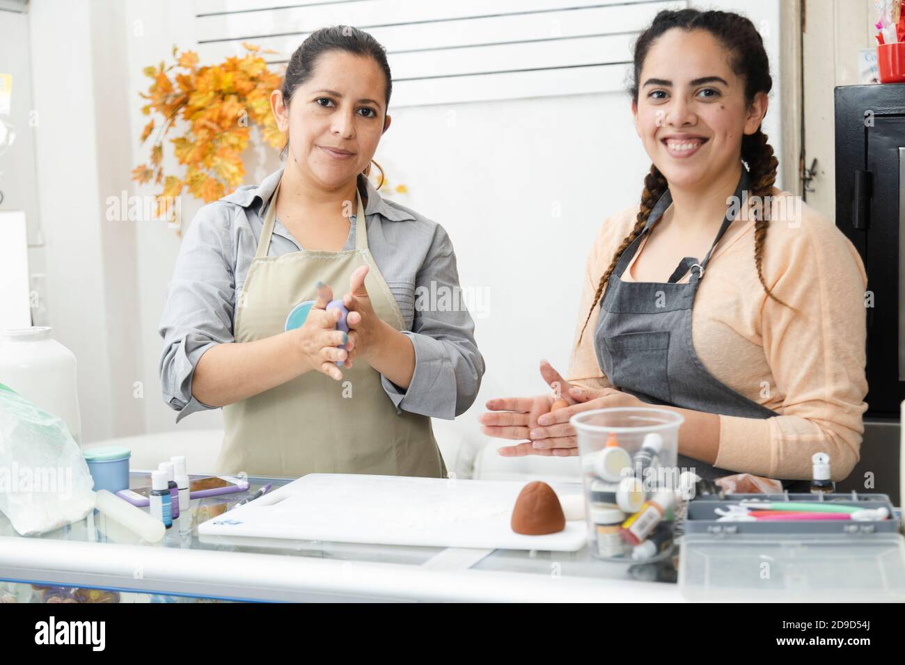 Lateinische Frauen, die in ihrer Bäckerei arbeiten - Frauen Konditorinnen Arbeiten mit Fondant, um einen Kuchen zu dekorieren - hispanische Frauen Unternehmer Stockfoto