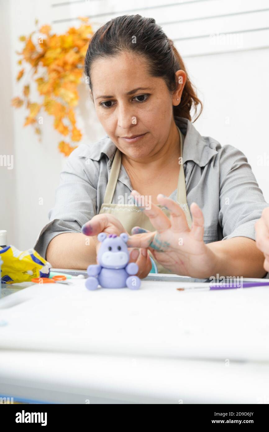 Hispanische Frau, die in ihrer Konditorei arbeitet - Latina Frau Arbeiten mit Fondant, um einen Kuchen zu dekorieren - Unternehmer Gebäck Koch - Frau, die Handwerk mit Stockfoto