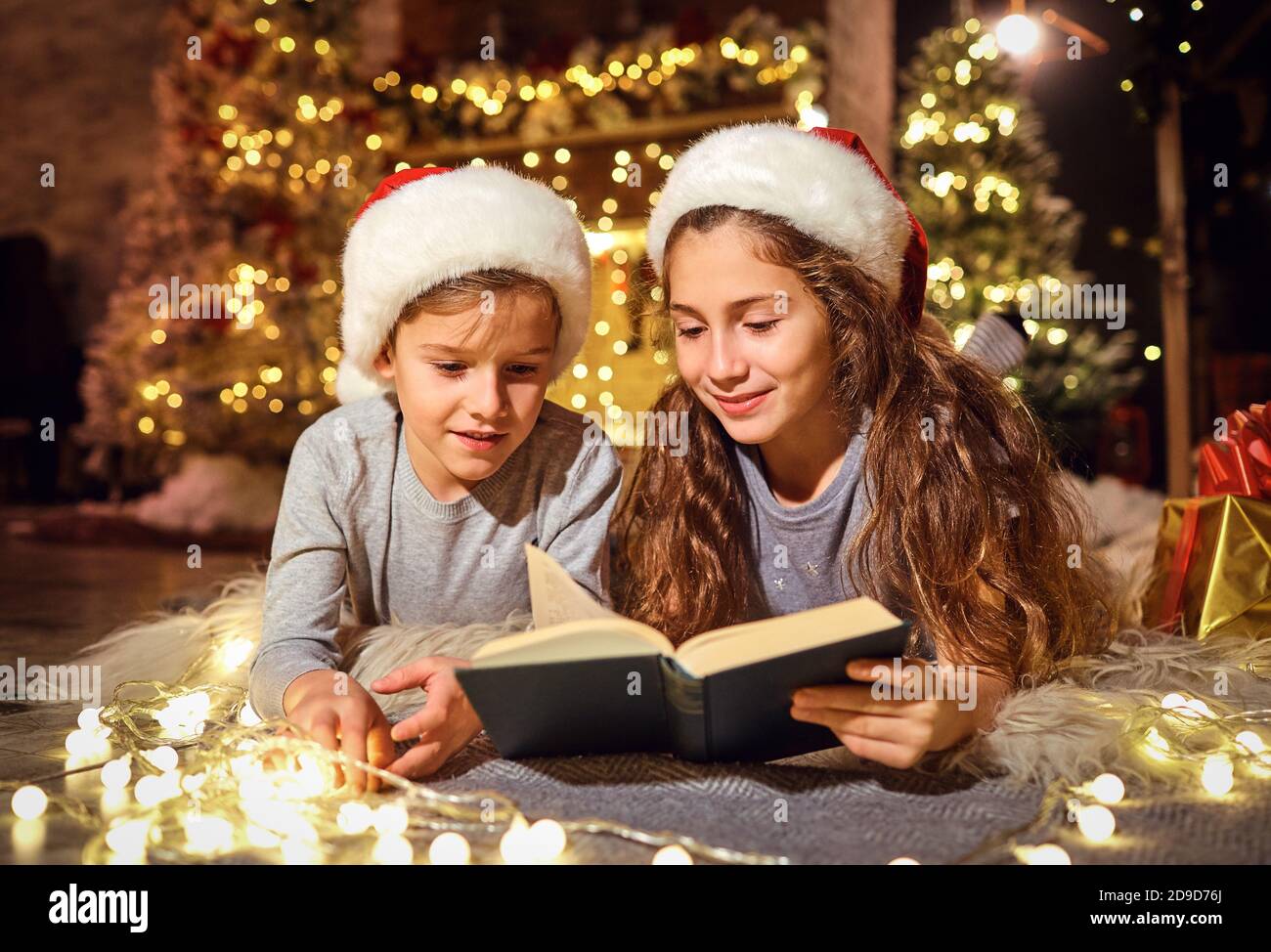 Kinder lesen zu Weihnachten ein Buch im Zimmer. Stockfoto