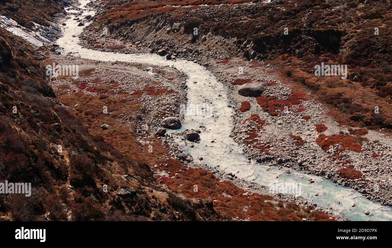 Luftaufnahme des oberen Dudhkoshi (Dudh Koshi)-Tals mit dem verdrehten eisigen Fluss, umgeben von rot verfärbten Büschen in der Herbstsaison in Khumbu, Nepal. Stockfoto