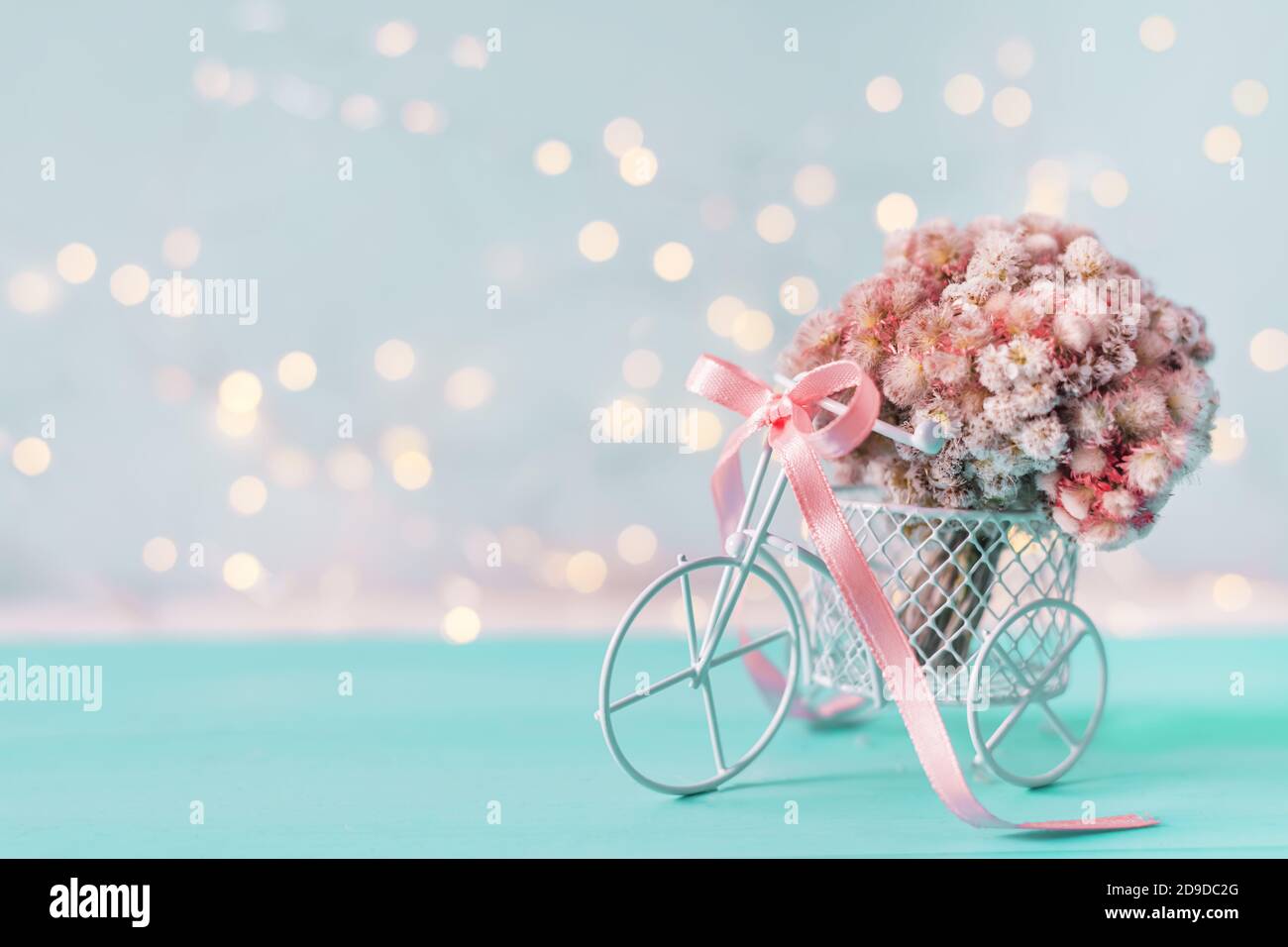 Retro Fahrrad mit Korb von rosa Blumen auf hellblauem Hintergrund. Stockfoto