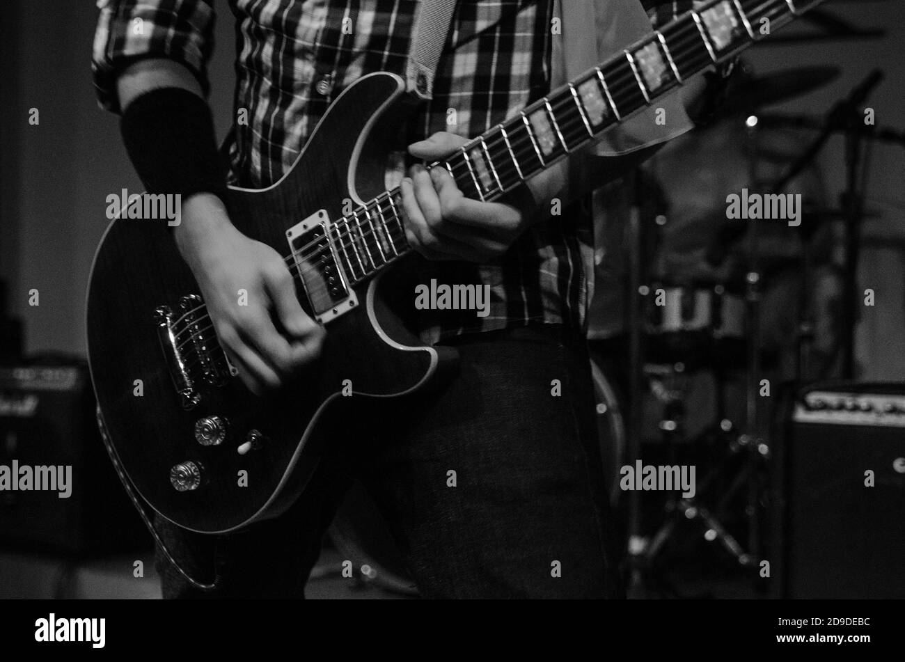 Graustufenaufnahme einer jungen Person, die Gitarre spielt Stockfoto