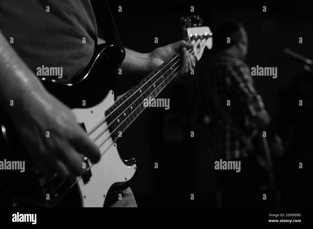 Graustufenaufnahme einer jungen Person, die Gitarre spielt Stockfoto