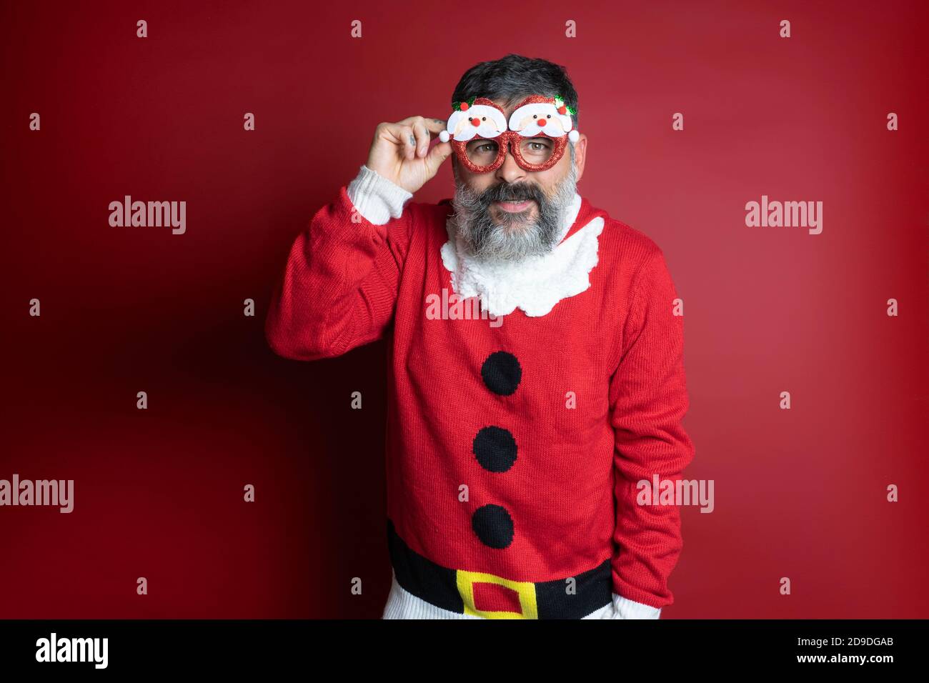 Studio Portrait eines bärtigen Mannes in engem weihnachtsmann Hut und weihnachtskleidung. Nahaufnahme, Platz für Text kopieren, Hintergrund isolieren. Stockfoto