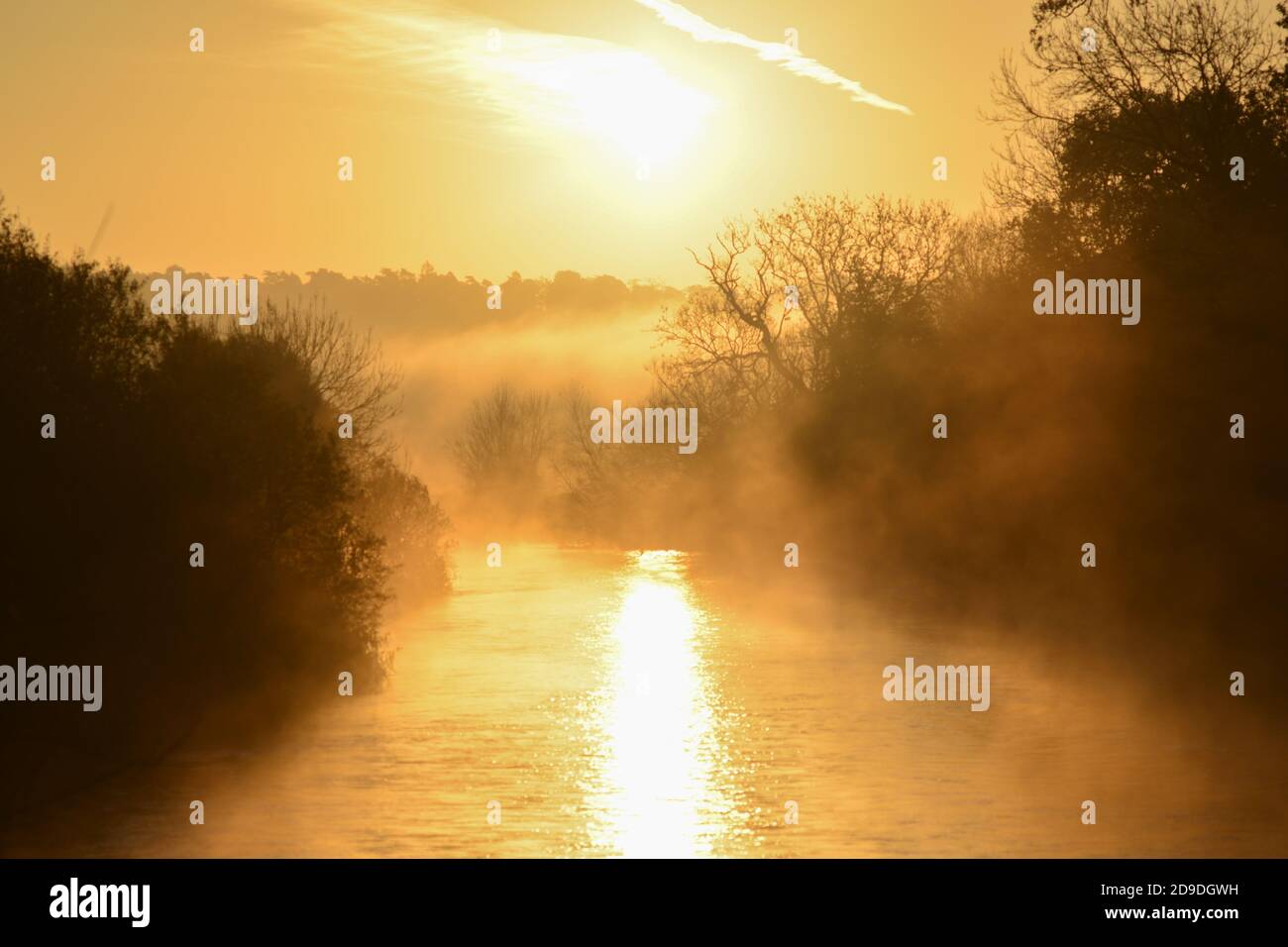 Kalter, frostiger, nebeliger Morgen mit warmem orangenem Sonnenaufgang, der sich im Flusswasser spiegelt, Fluss Avon, Avon Valley, Fordingbridge, New Forest, Hampshire, Großbritannien, 5. November 2020, Wetter, Landschaft. Stockfoto