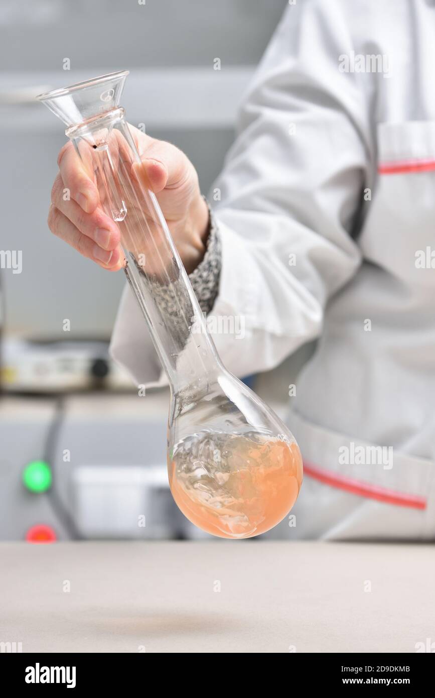 Weibliche Laborassistentin mischt Flüssigkeit in einem Reagenzglas ein Das Labor Stockfoto
