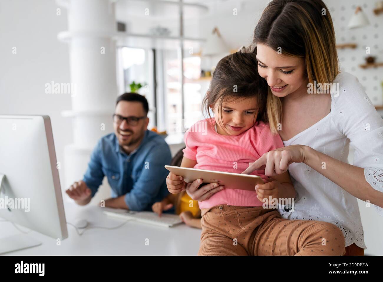 Online-Schule, Technologie, Familienkonzept. Glückliche Eltern helfen Kindern, zu Hause zu lernen Stockfoto