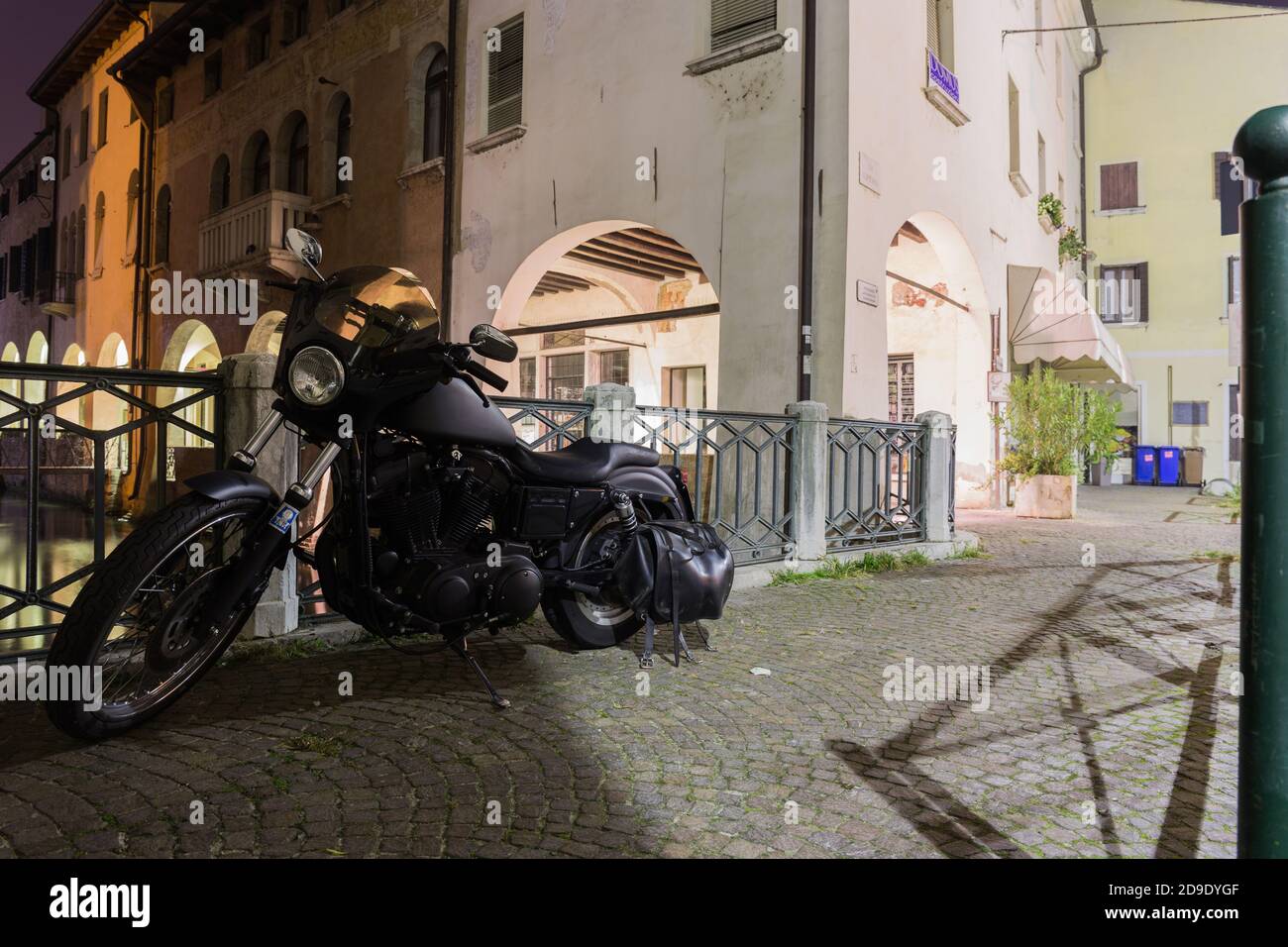 Amerikanisches Motorrad geparkt in der Nähe eines Zauns auf einer Brücke im Kanal Buranelli in der Nacht. Treviso Italien Stockfoto