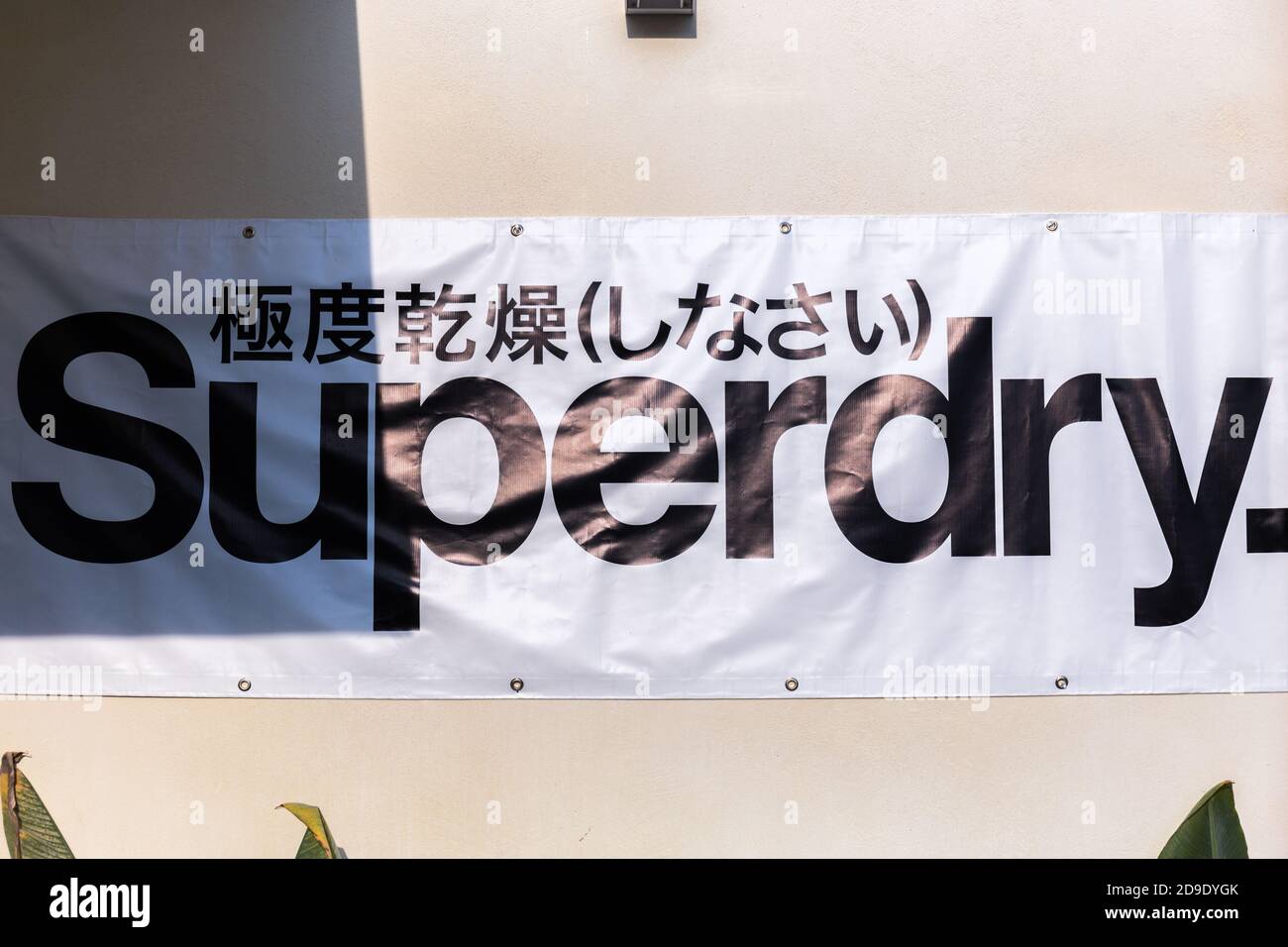 Superdry Bildunterschrift hängt an einer Wand auf weißem Hintergrund Name Von berühmten Bekleidungsunternehmen Stockfoto