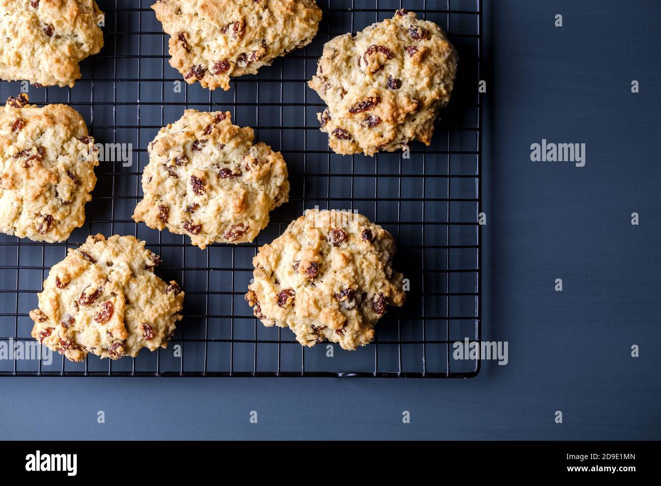 Eine frisch gebackene Partie Rock Cakes, oder Rock Buns, auf einem Kühlregal. Die schmackhaft aussehenden Kuchen sind mit Sultaninen und Rosinen gefüllt Stockfoto