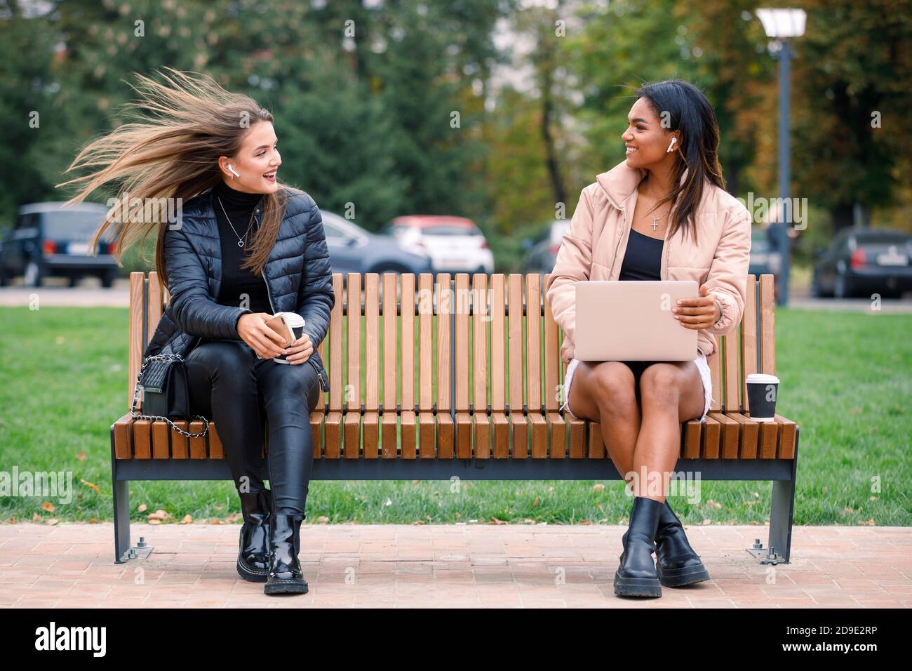 Zwei Frauen plaudern auf der Bank mit sozialer Distanzierung Stockfoto