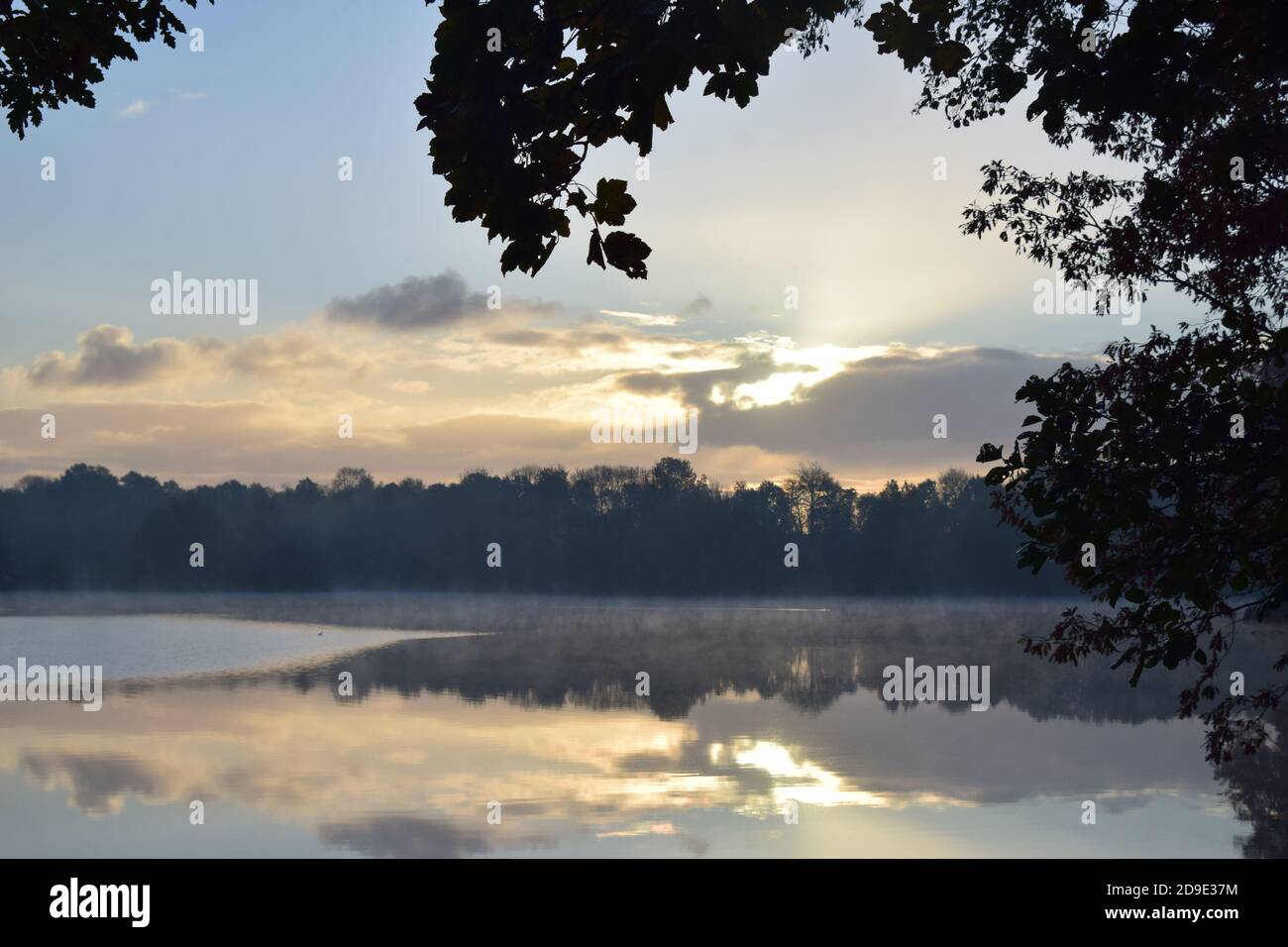 Erste Vorführung mit anhaltendem Nebel über der Oberfläche der Seen Bilden eines Spiegels, der die Muster des Himmels auf seiner Oberfläche reflektiert Stockfoto