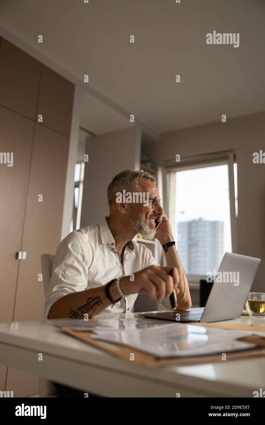 Männlich mit einem Chat auf dem Handy in seinem Arbeitszimmer Stockfoto