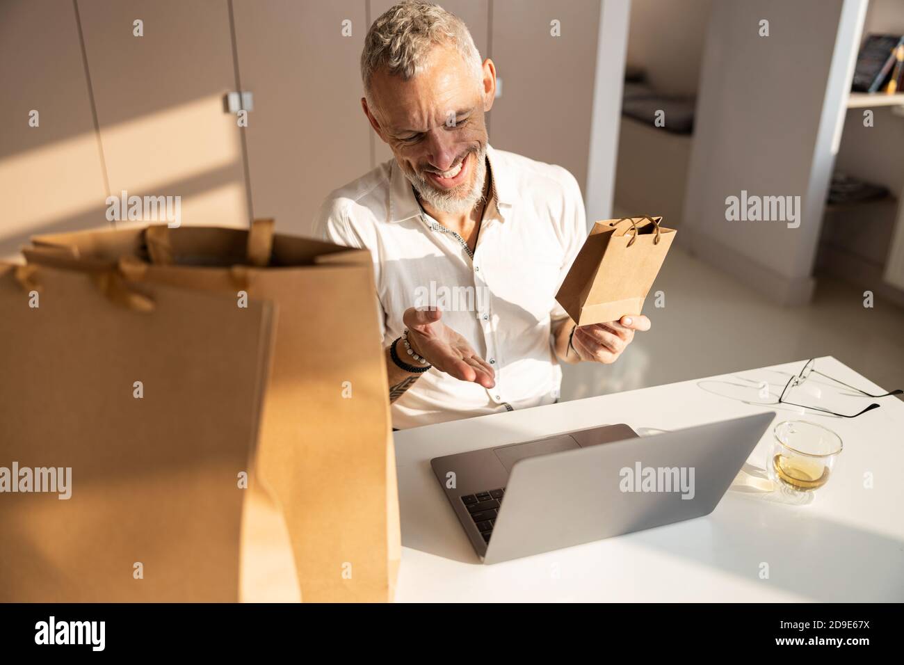Sorgloser männlicher Arbeiter, der einer Webcam eine Tasche zeigt Stockfoto