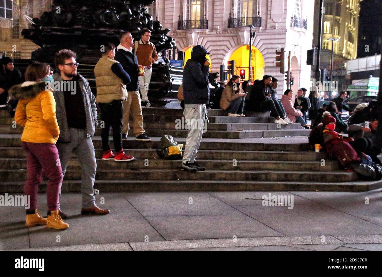 London, Großbritannien. November 2020. Menschenmassen sitzen am Vorabend der 2. Sperre im Londoner Piccadilly Circus um die Eros Statur.der Abend der Lockdown 2 - der Abend bevor England am 5. November für vier Wochen in Lockdown geht. Kredit: SOPA Images Limited/Alamy Live Nachrichten Stockfoto