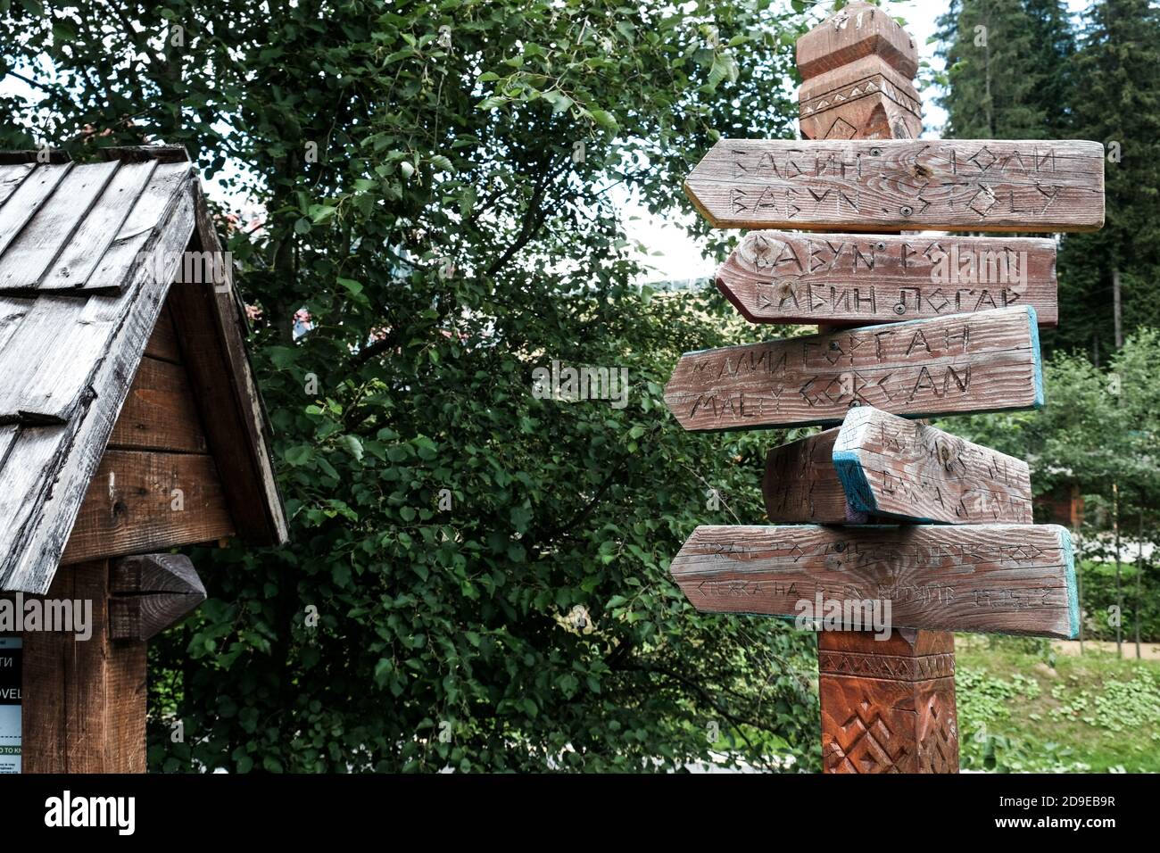 Bukovel, Ukraine - Juli 2020: Straßengabel in ländlichen ukrainischen Dorf. Traditionelle Holzbretter oder Platten mit Pfeilen und geschnitzten Ortsnamen in Bukovel. Stockfoto