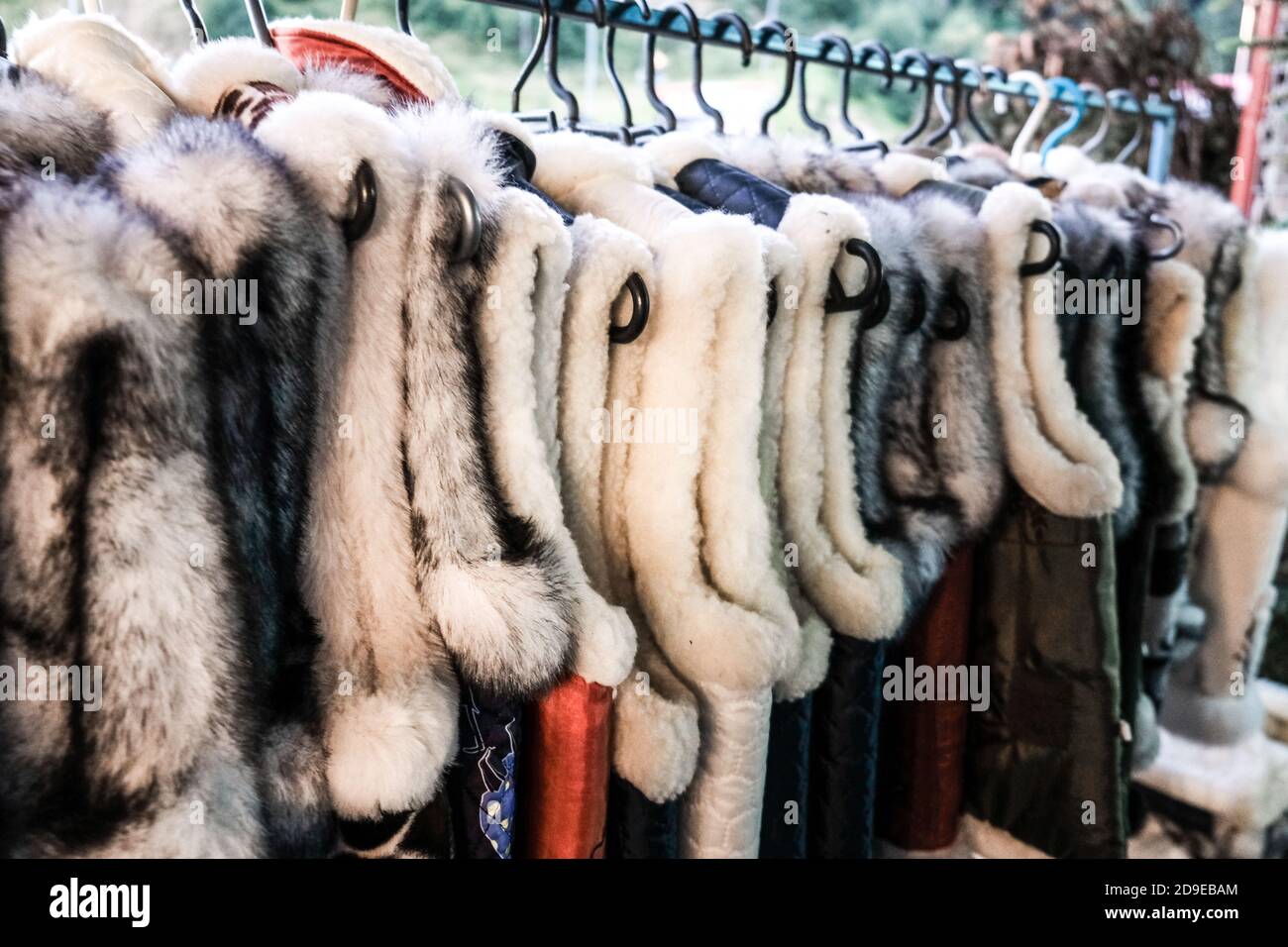Ein Bündel von traditionellen ukrainischen Pelzwesten hängen zum Verkauf in einem Outdoor-Shop in einem ländlichen Dorf in der Ukraine. Handgemachte Handwerkskunst auf einer lokalen Messe. Stockfoto