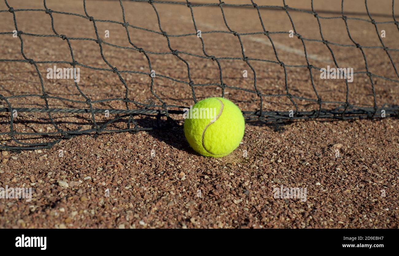 Tennisball vor dem Hintergrund eines Netzes auf einer schmutzigen Oberfläche. Stockfoto