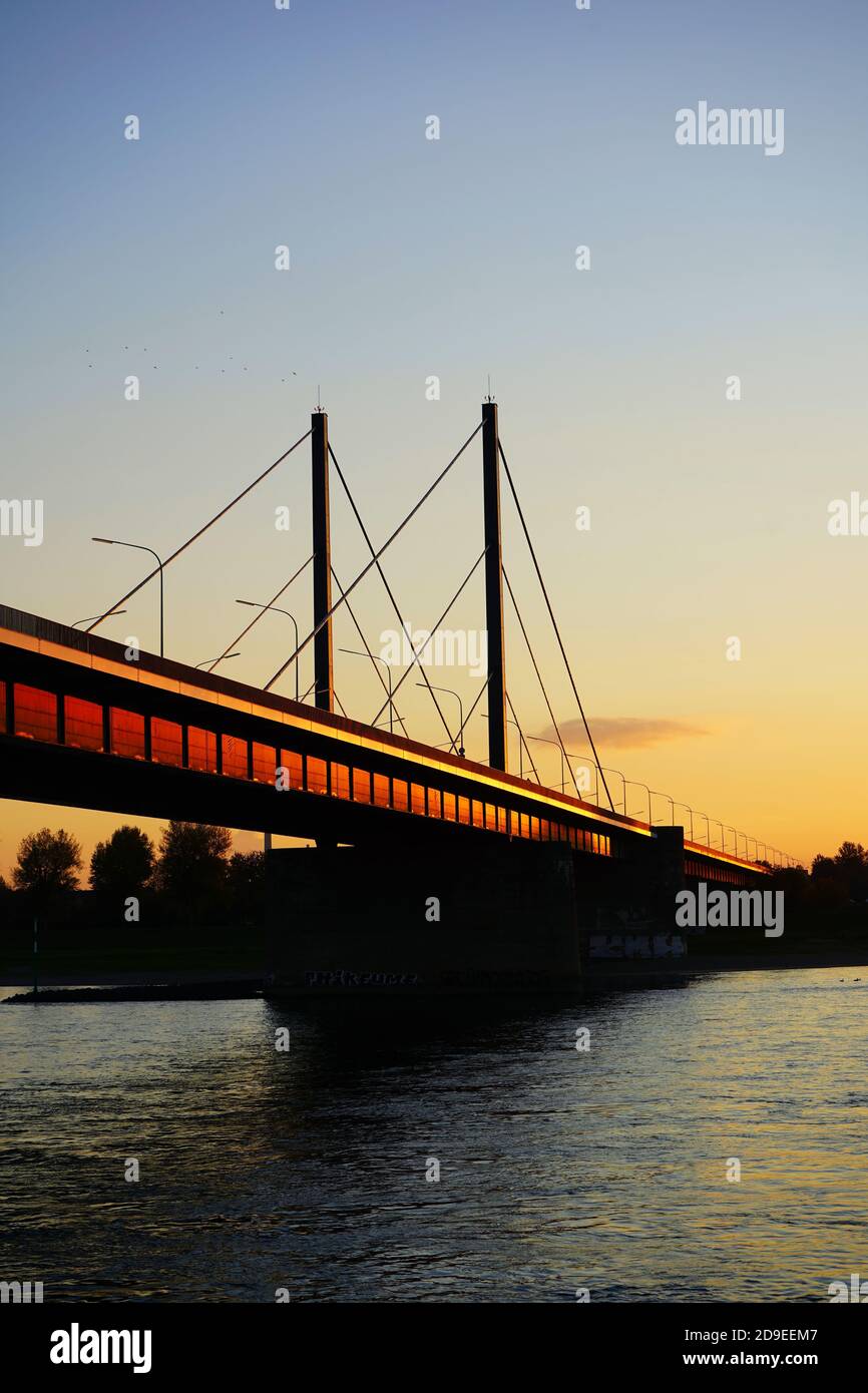 Theodor-Heuss-Brücke, die erste Seilbrücke in Deutschland, mit Spiegelung der untergehenden Sonne. Stockfoto