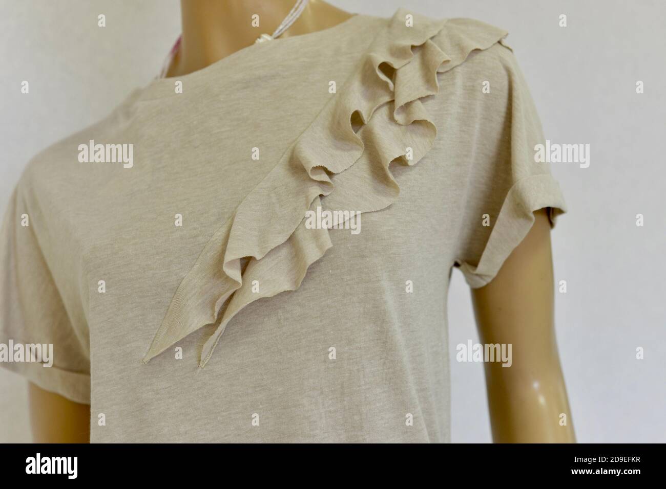 Damen-T-Shirt mit Rüschen. Farbe sanft sandig beige pudrig. Fragment Nahaufnahme. Für Geschäfte. Stockfoto
