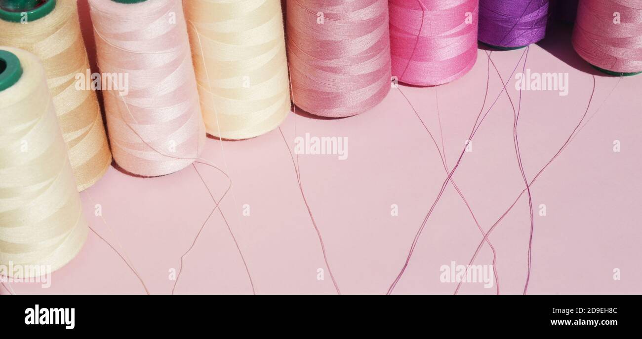 Fäden in verschiedenen Farben auf einem rosa Hintergrund. Banner. Platz für Text kopieren. Stockfoto