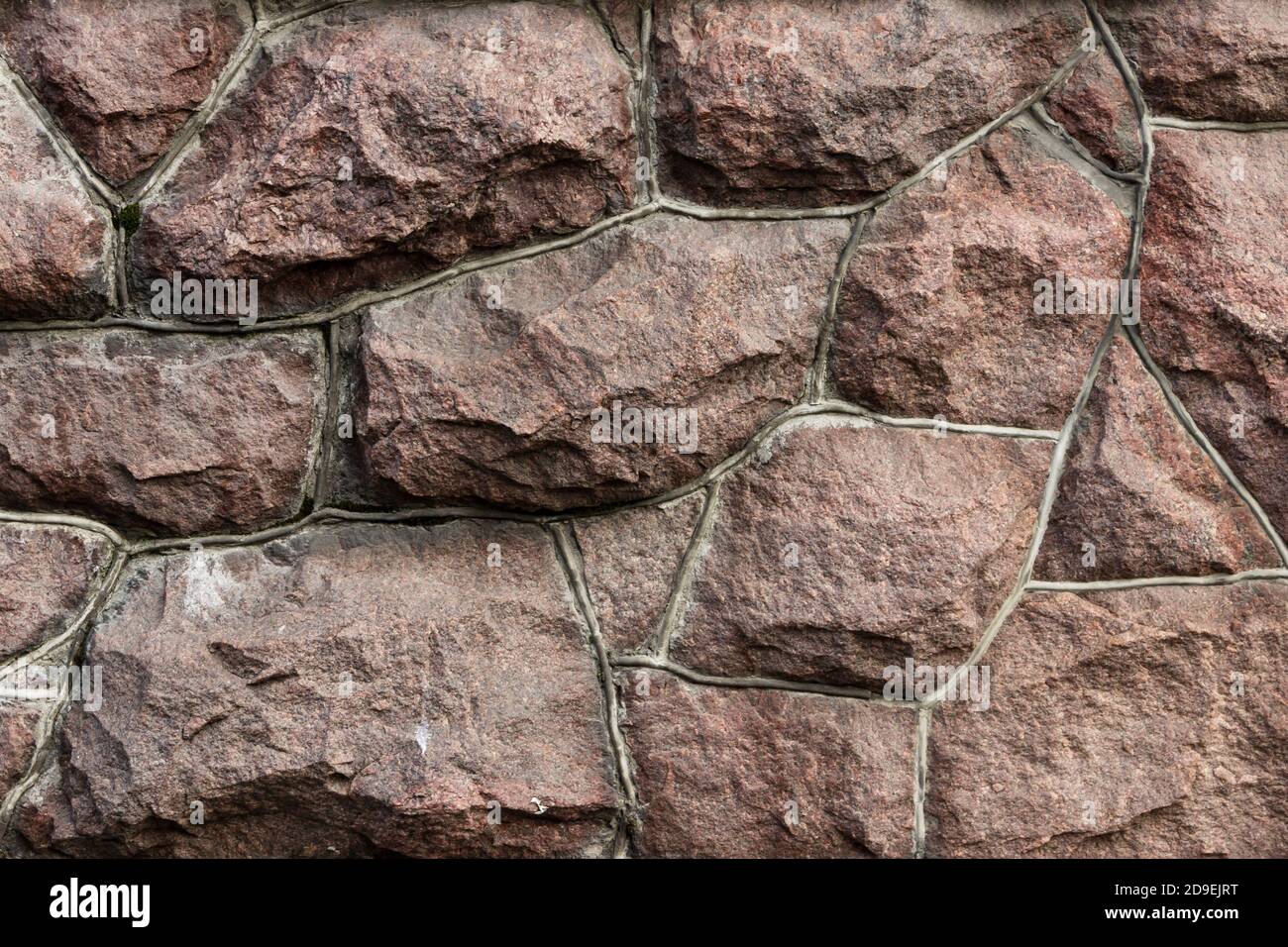 Die Oberfläche des Mauerwerks besteht aus grob behauenen großen roten Steinen, die miteinander verbunden sind. Stockfoto