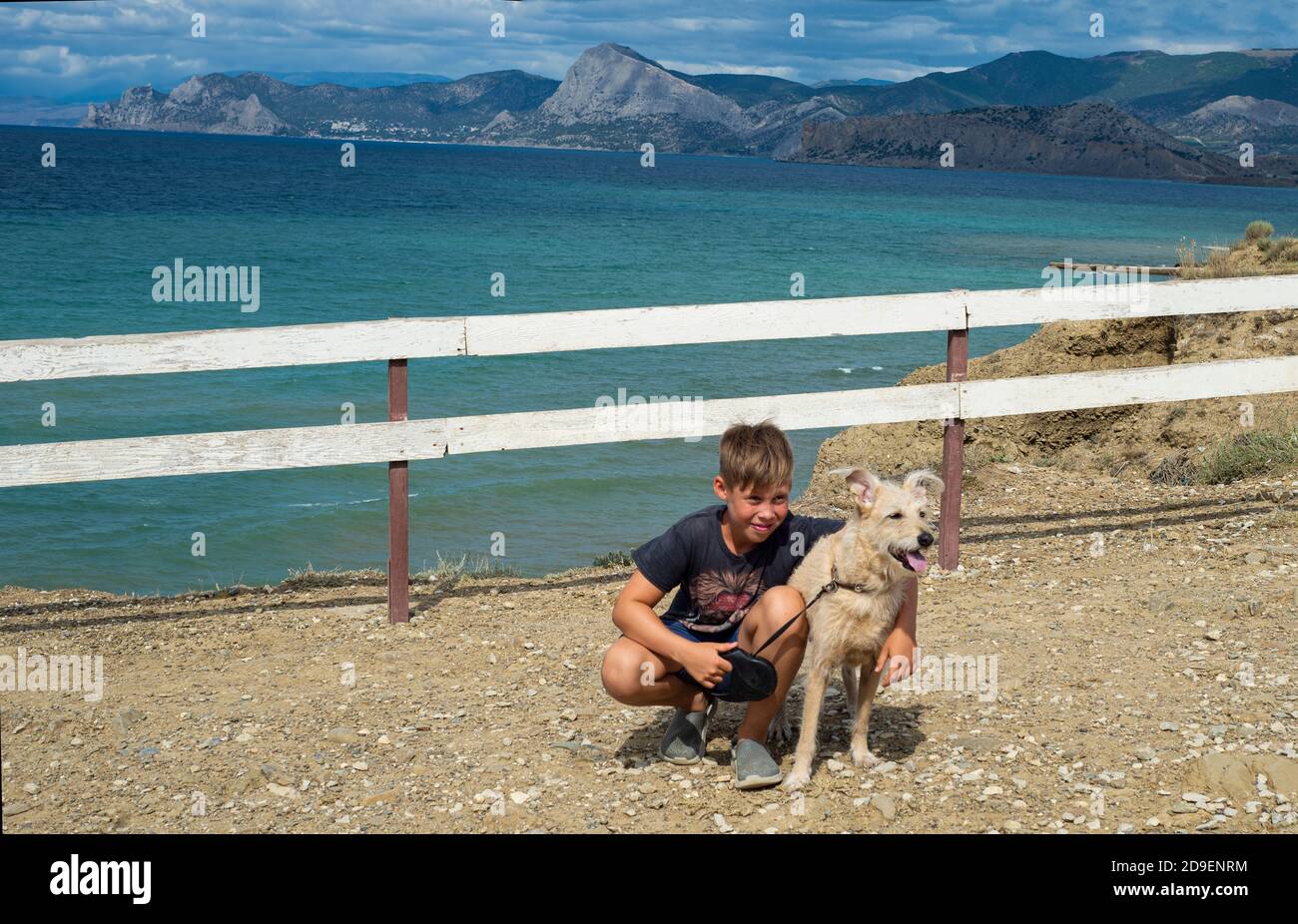 Junge mit Hund auf dem Hintergrund der Meereslandschaft. Freundschaft von Kindern mit Haustieren. Reisen mit Ihren Haustieren. Platz für Text kopieren. Stockfoto