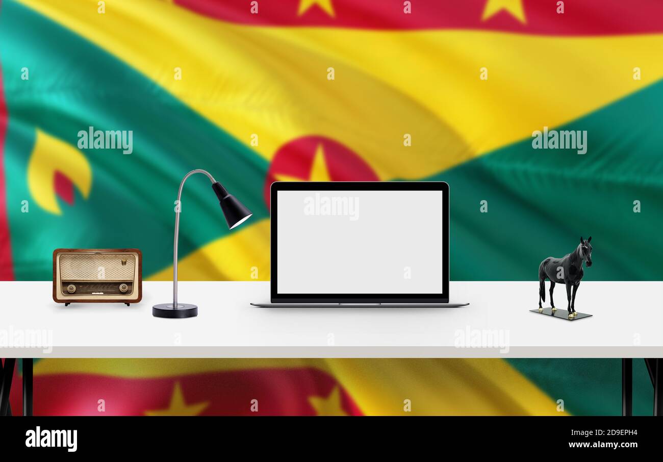 Grenada Nationalflagge Hintergrund mit Arbeitsplatz, Desktop-Computer und Office-Zubehör auf weißem modernen Tisch. Stockfoto