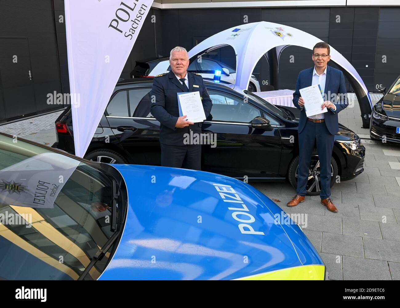 05. November 2020, Sachsen, Zwickau: Horst Kretzschmar (l.), Staatspolizeipräsident Sachsen, und Reinhard de Vries, Geschäftsführer Technik und Logistik von Volkswagen Sachsen, stehen mit Kooperationsvertrag vor einem VW Golf-Spezialpolizeifahrzeug. Volkswagen Sachsen und die sächsische Polizei haben eine Kooperationsvereinbarung über die künftige Zusammenarbeit unterzeichnet. In Zukunft wird die Polizei in der Lage sein, aktuelle VW-Fahrzeuggenerationen intensiv in der Praxis zu testen. Im Gegenzug erhält der Automobilhersteller Erkenntnisse in der Entwicklung von speziellen Polizeifahrzeugen. Das Projekt beginnt mit zwei zivilen Stockfoto