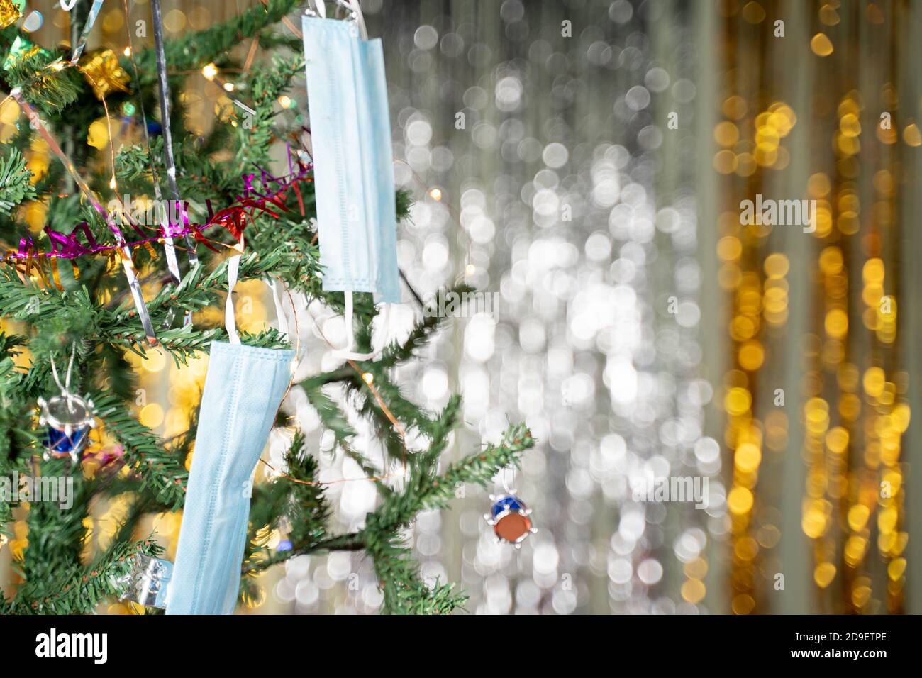 Nahaufnahme von dekorierten Weihnachtsbaum mit medizinischer Maske - Konzept von Covid-19, Coronavirus und Weihnachtsfeiertag Stockfoto