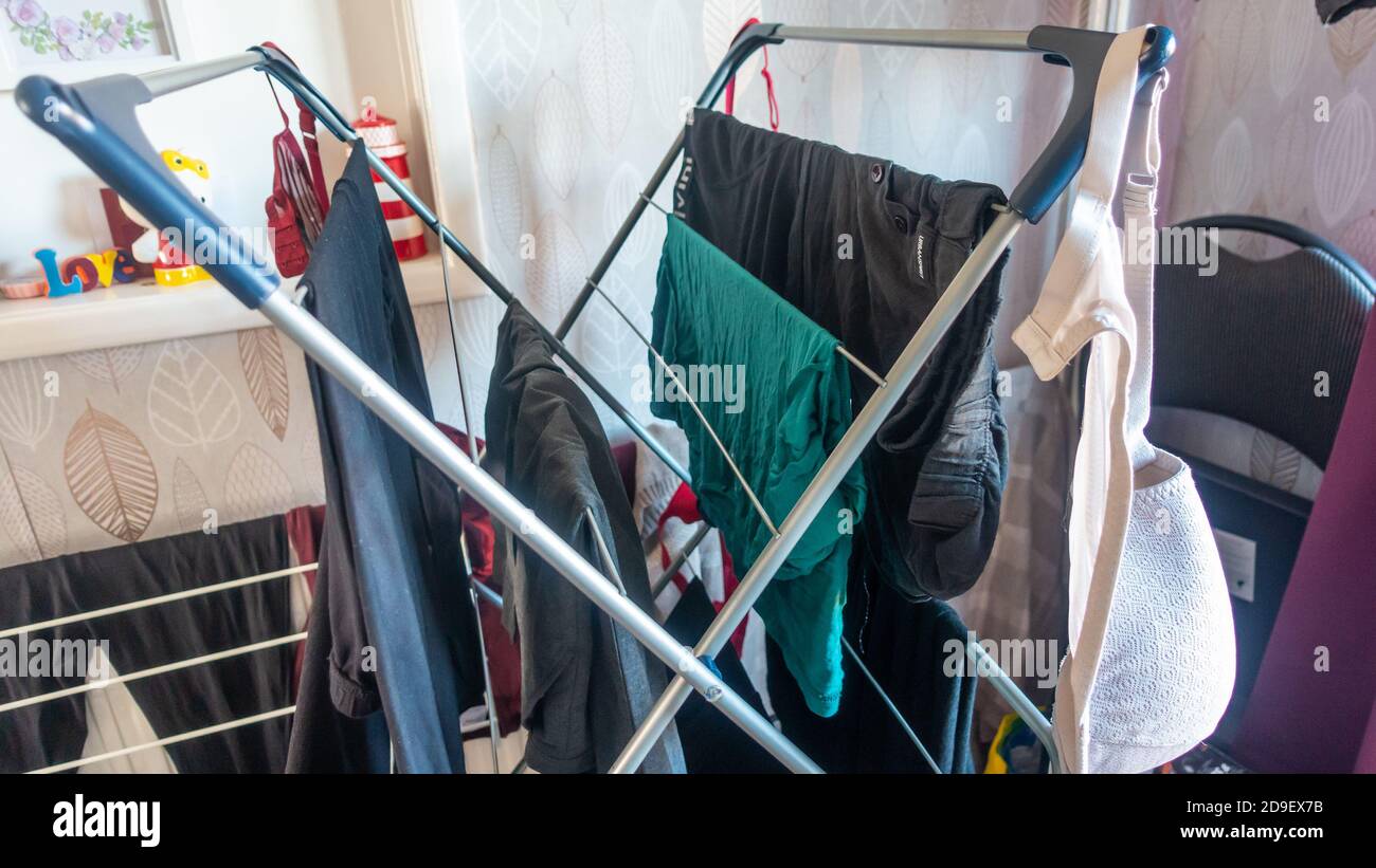 Trocknen von kürzlich gewaschenen Kleidungsstücken im Innenbereich auf einem Trockengestell. Stockfoto