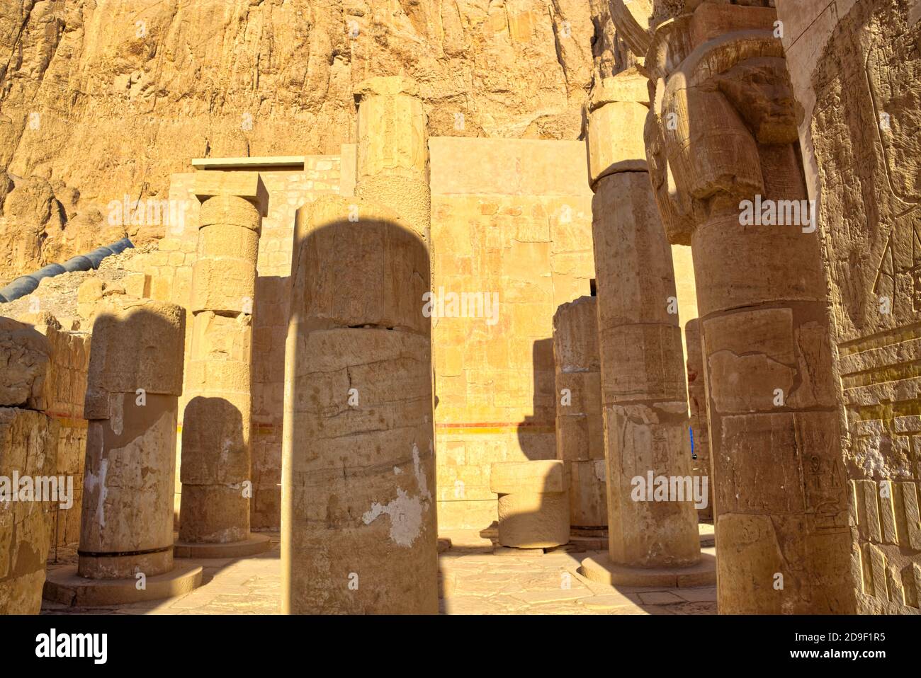 Einige quadratische Pfeiler und runde Säulen sind mit Hathor Kapitellen gekrönt - mit Merkmalen der Göttin mit Kuhohren. Beachten Sie die Osirian Statue nur visibl Stockfoto