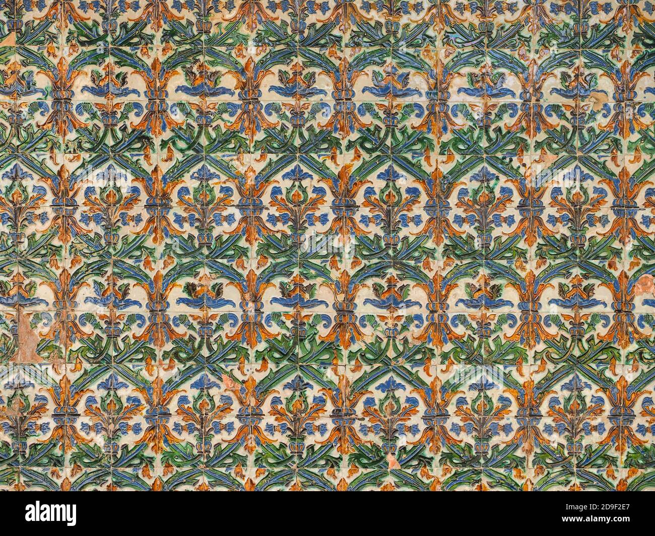 Fragment der Gebäudewand mit beschädigten, nicht korrigierten, Vintage-Keramik-Wandfliesen, Mudejar, Nahaufnahme. Abstrakt dekorativer Hintergrund, verziertes Muster. Stockfoto