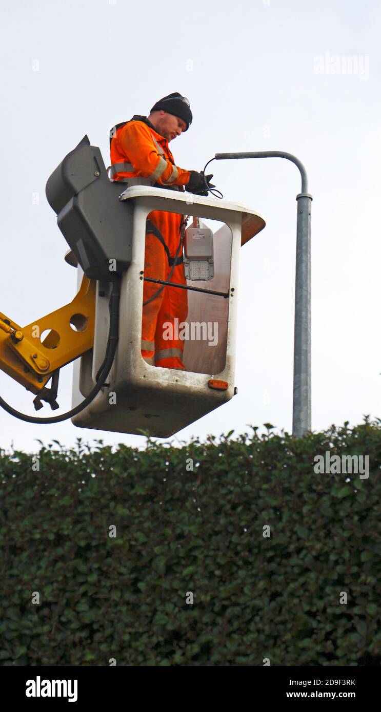 Ein Wartungstechniker, der eine Straßenbeleuchtung von einer auf einem Lkw montierten Zugangsplattform in Hellesdon, Norfolk, England, Großbritannien, bedient. Stockfoto