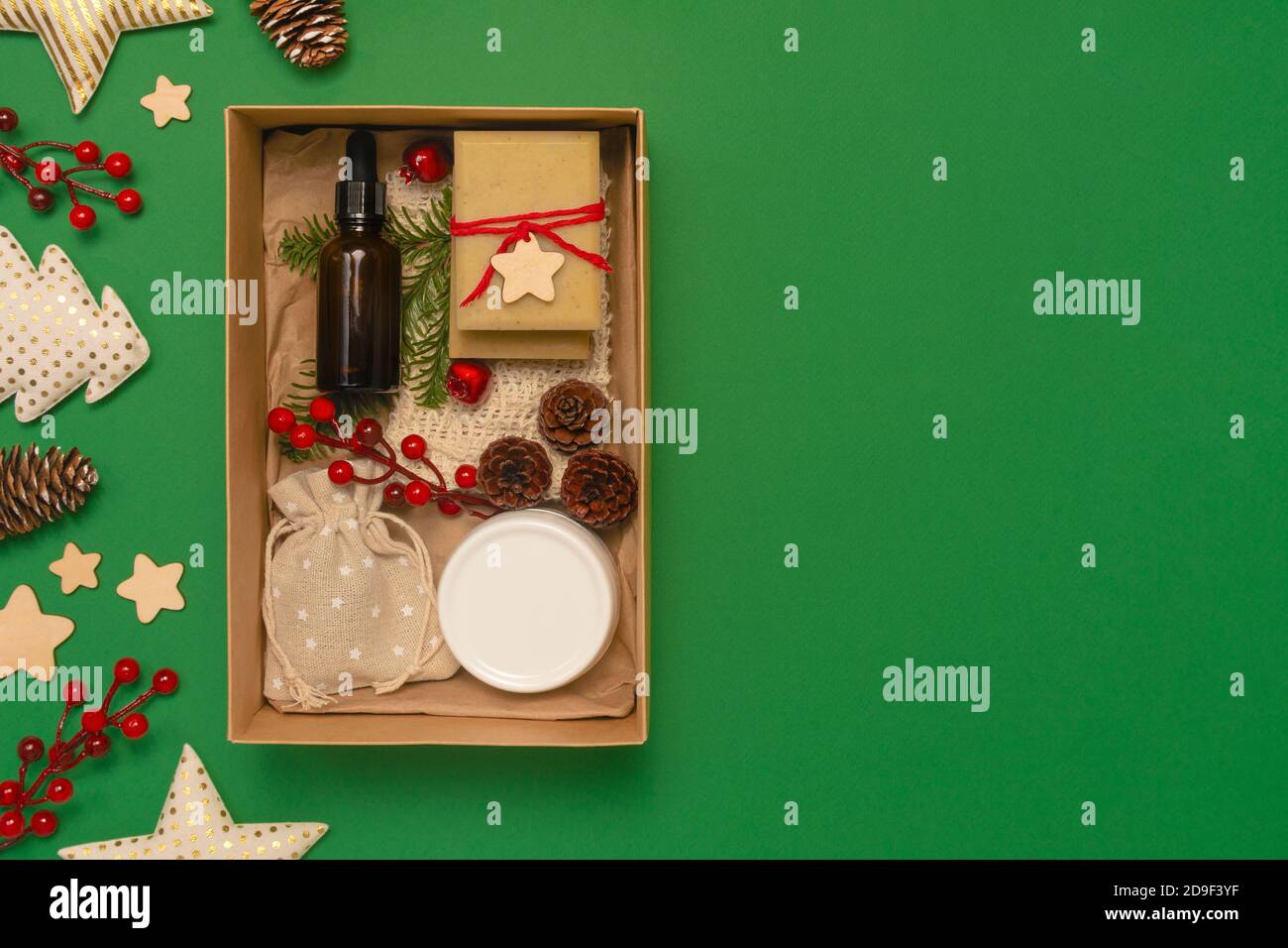 Geschenk-Box mit Bio-Kosmetik auf grünem Hintergrund. Glas, Holzdekorationen. Zero Waste Weihnachtskonzept. Flache Lay-Ansicht von oben, Kopierbereich Stockfoto