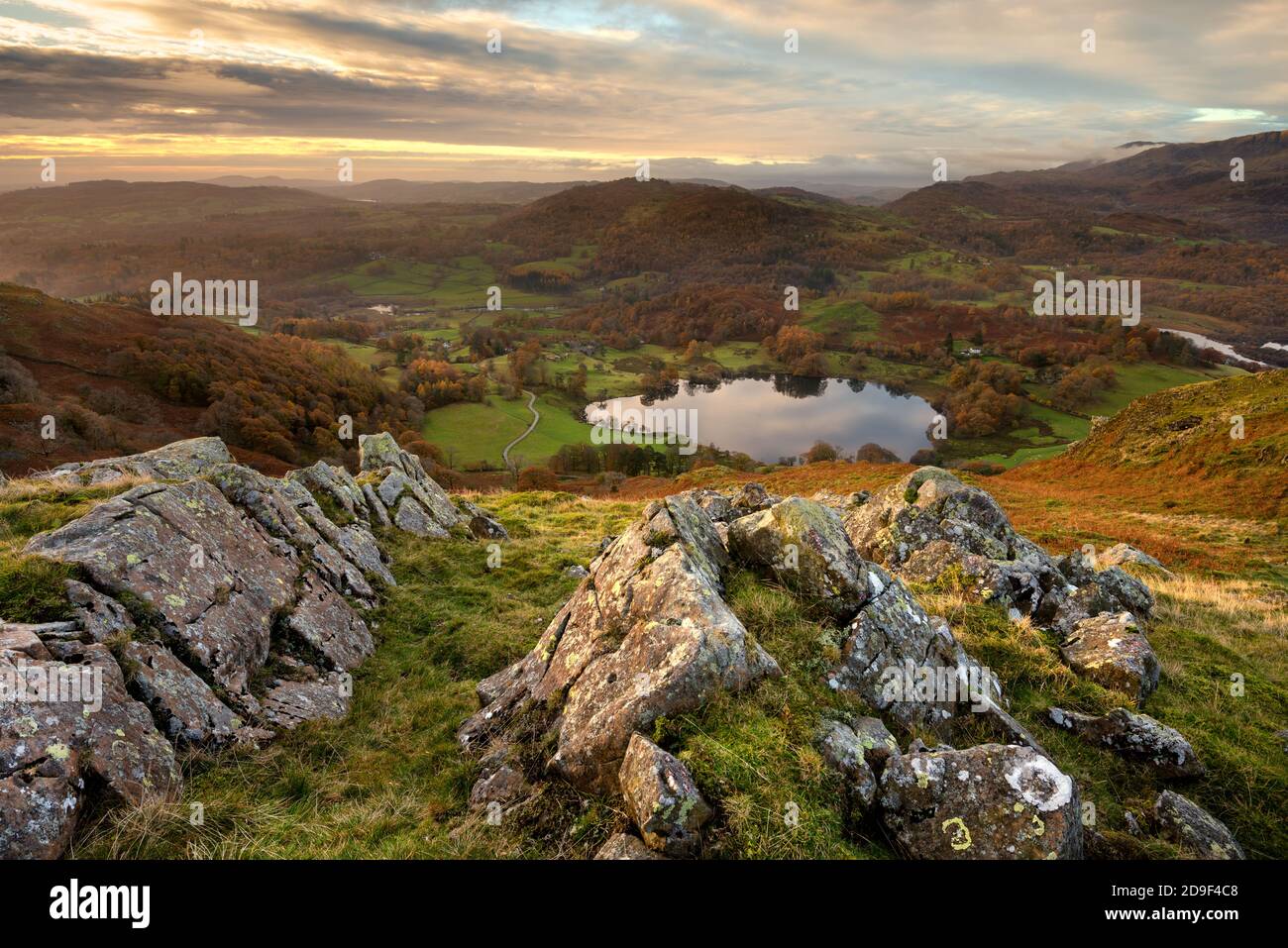 Luftaufnahme von Loughrigg Tarn mit Felsen im Vordergrund an einem schönen Herbstmorgen. Lake District, Großbritannien. Stockfoto