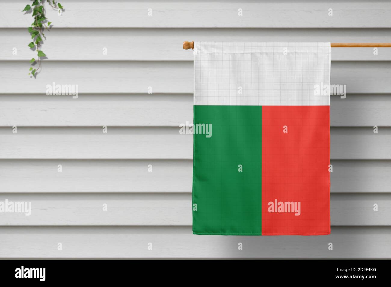 Madagaskar nationale kleine Flagge hängt von einem Pfostenzaun entlang der Holzmauer in einer ländlichen Stadt. Konzept des Unabhängigkeitstages. Stockfoto