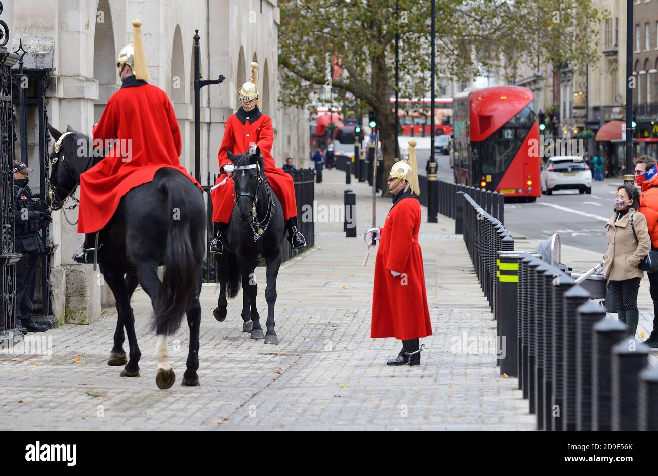 London, England, Großbritannien. Horse Guards auf Whitehall. Mitglieder der Haushaltskavallerie wechseln die Wache am Mittag, beobachtet von zwei Touristen tragen Facemas Stockfoto