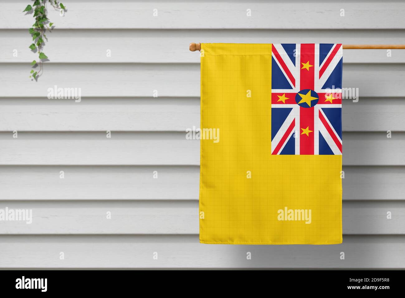 Niue nationale kleine Fahne hängt von einem Pfostenzaun entlang der Holzmauer in einer ländlichen Stadt. Konzept des Unabhängigkeitstages. Stockfoto