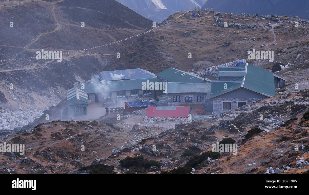 Sherpa Lodges in Steinhäusern mit grünen Wellblechdächern und rauchenden Kaminen am Abend auf dem anspruchsvollen Everest Base Camp Trek. Stockfoto