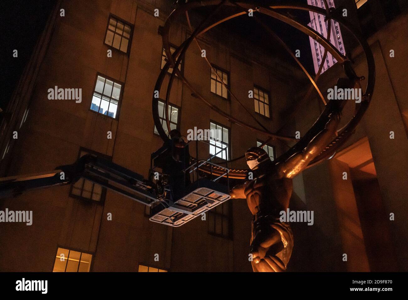 NEW YORK, NY - 04. NOVEMBER 2020: Ein Arbeiter legt eine Gesichtsmaske für die Atlas-Skulptur vor dem Rockefeller Plaza 45 an. Stockfoto