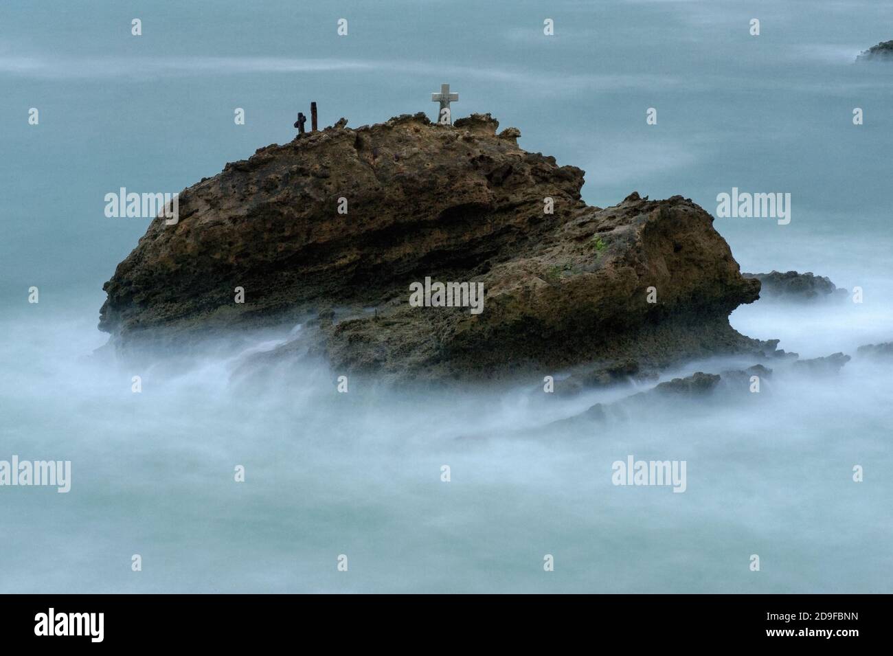 La Roche Battue (der zerschlagene oder geschlagene Felsen), der bei Flut nicht weit in die stürmische Bucht von Biscay vor dem Grand Plage Strand in Biarritz, Nouvelle-Aquitaine, Frankreich, liegt. Sie trägt ein beschriftete Kreuz und andere Gedenkstätten an die ertrunkene fünfköpfige Besatzung der Schlinge ‘La Surprise’, die in rauschenden Meeren Segel und Ruder verlor, während sie Schiefer von Bayonne nach London, England, transportete. Das Schiff lief am nächsten Tag, dem 17. November 1893, auf La Roche Battue, auch bekannt als l’Arroque Trudade, auf Grund. Ein Mann wurde tot aufgefunden, aber die Leichen der anderen vier wurden nie geborgen. Stockfoto