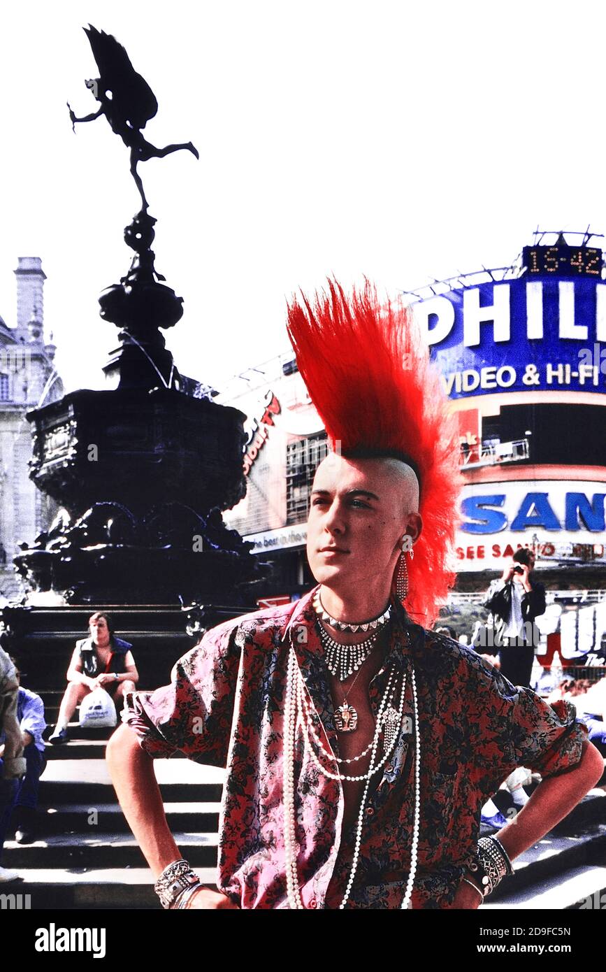 London Punk Rocker Matt Belgrano posiert neben der Statue von Eros, Piccadilly Circus, London, England, UK. Ca. 1980 Stockfoto