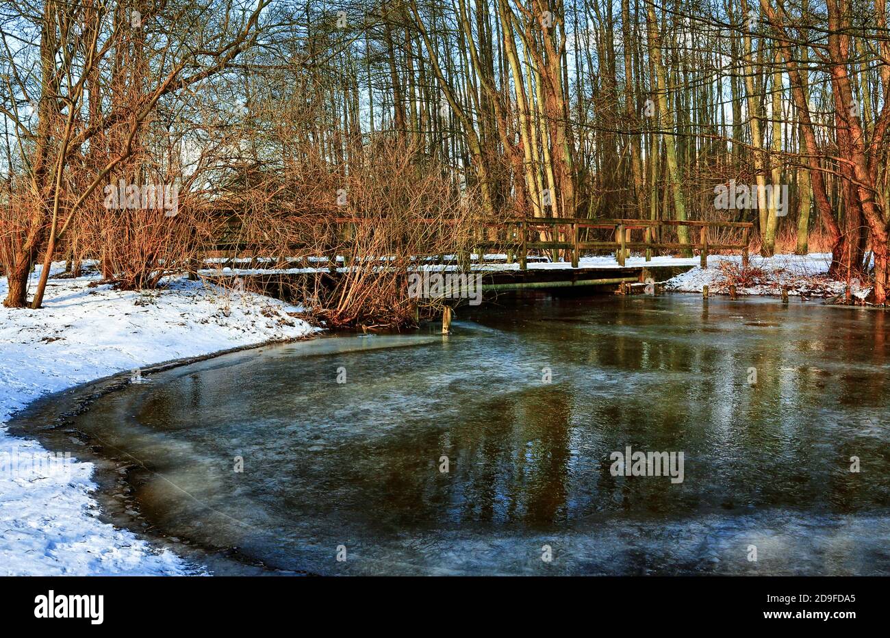 Holzbrücke über den gefrorenen Malenter Au (kleiner Fluss in Holstein Schweiz). Stockfoto