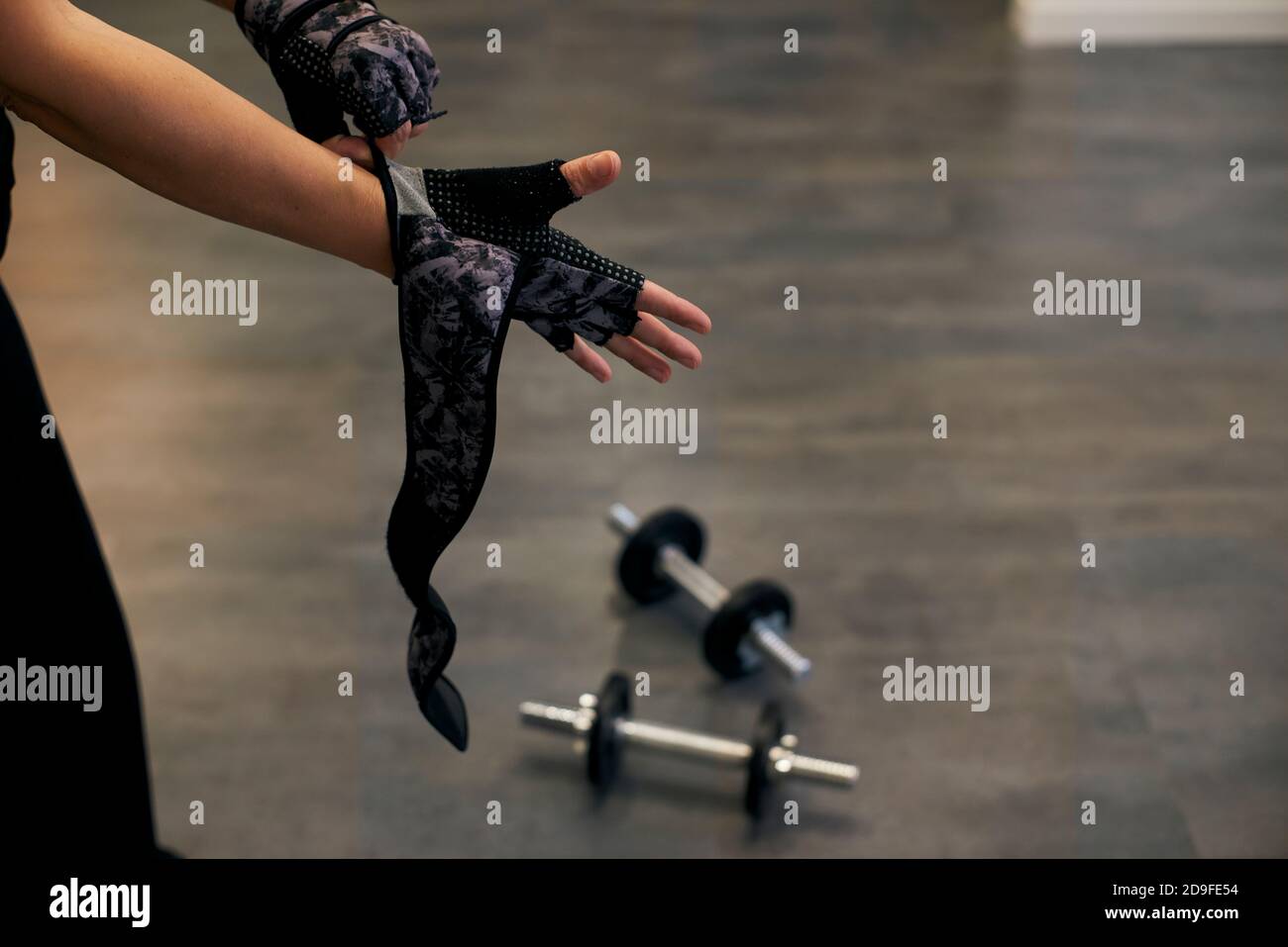 Eine Frau, die Sporthandschuhe für das Krafttraining anziehen. Schulungskonzept Stockfoto