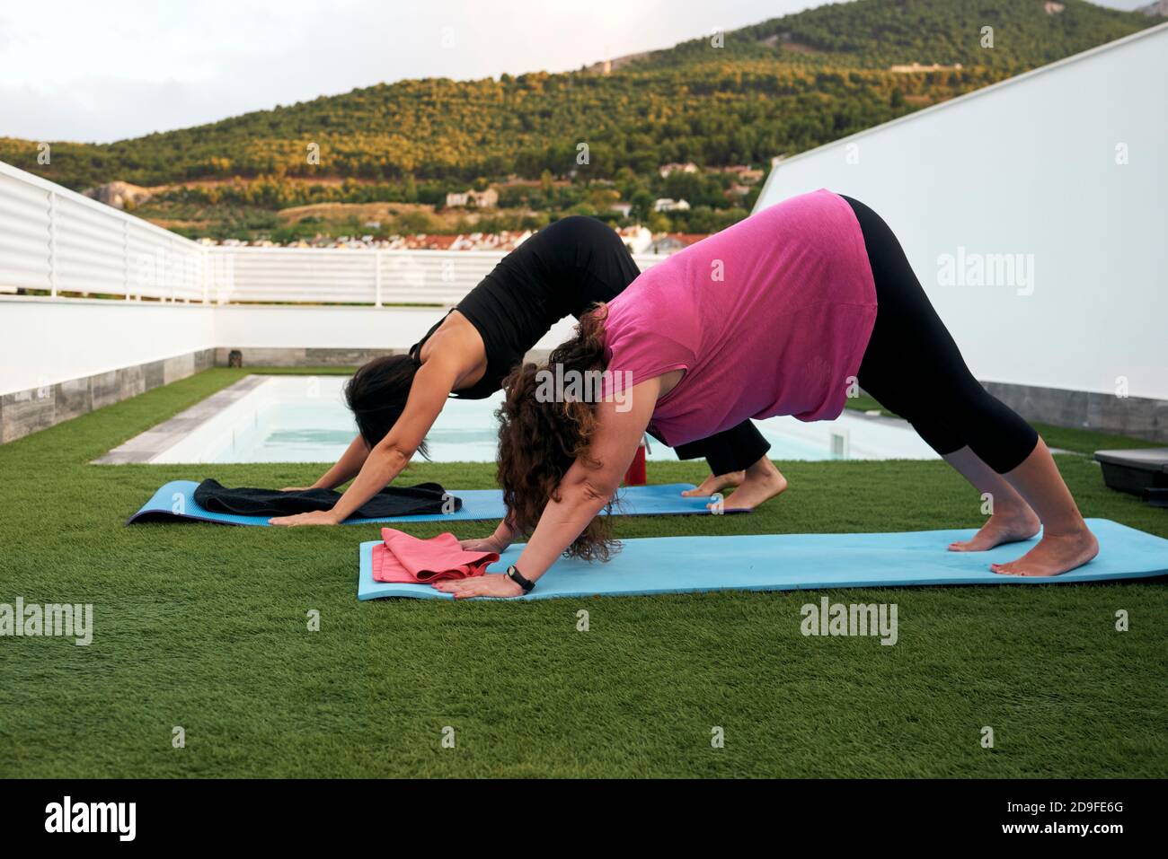 Frauen machen Yoga auf der Terrasse des Hauses, mit dem Gesicht nach unten Hundehaltung Stockfoto