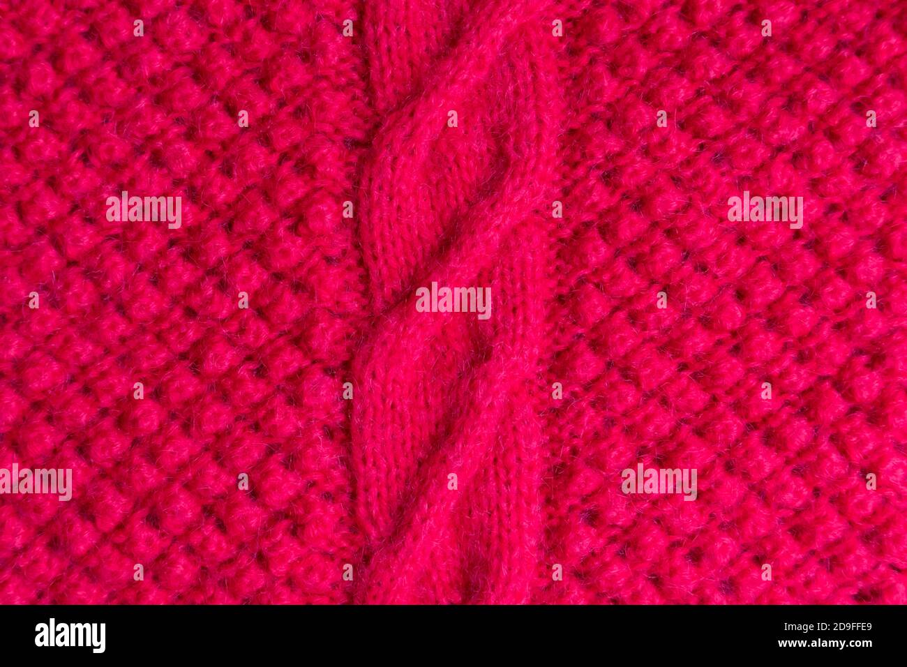 Der rote Strickstoff mit strukturiertem Muster wird von Hand gefertigt. Hintergrund. Stockfoto