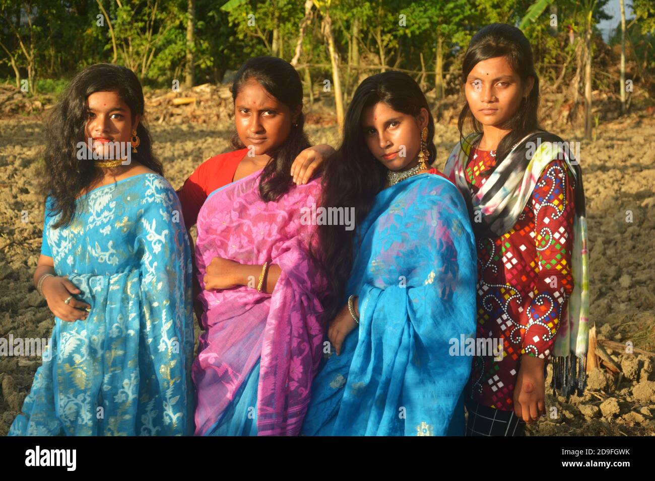 Vier schöne Teenager indischen bengalischen Mädchen mit langen dunklen Haaren tragen Sari und Schmuck wie goldene Ohrringe Halskette auf einem Feld, Sel Stockfoto