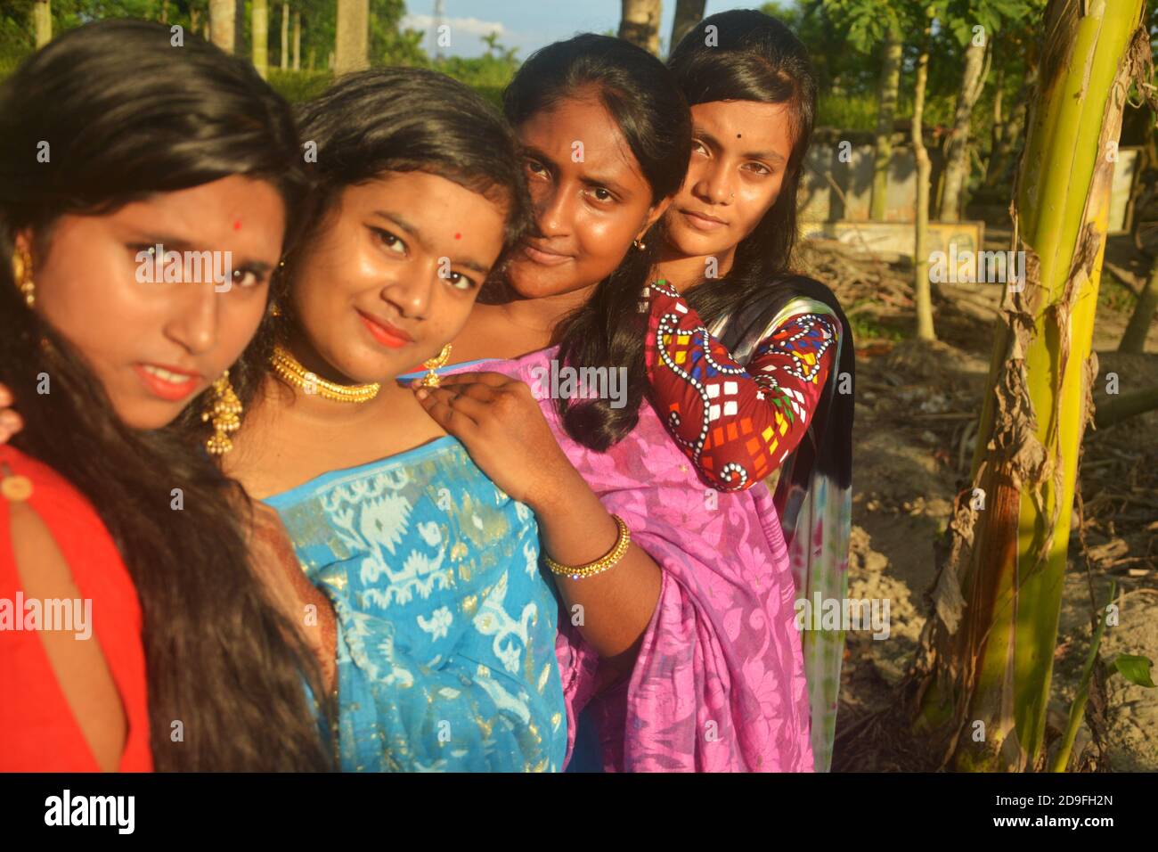 Nahaufnahme von vier schönen Teenager indischen Bengali Mädchen mit langen dunklen Haaren tragen Sari und Schmuck wie goldene Ohrringe Halskette, Wahlfokus Stockfoto