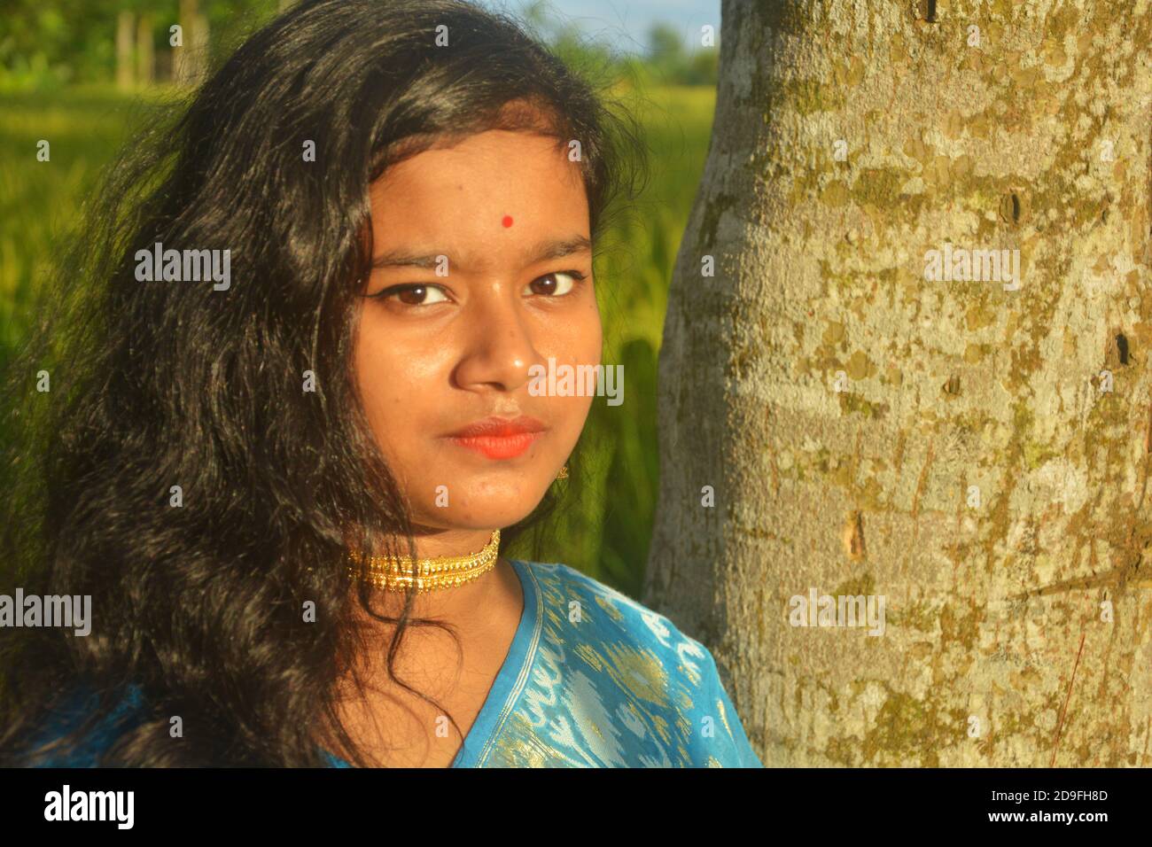 Nahaufnahme eines indischen Teenagers mit Sari, goldener Halskette und Bindi auf der Stirn mit langen dunklen Haaren, selektive Fokussierung Stockfoto